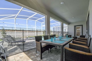 Un patio cubierto con mobiliario exterior, una piscina y vistas del paisaje circundante.