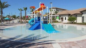 A water park with slides and a pool, surrounded by palm trees and buildings. - 6BR resort home with private pool, game room & golf access. (Kissimmee)