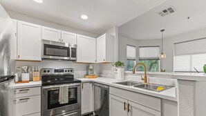 A modern kitchen with stainless steel appliances, white cabinetry, and a built-in dishwasher. -  Best Scottsdale location. Shopping, Food, Golf, near (Scottsdale)