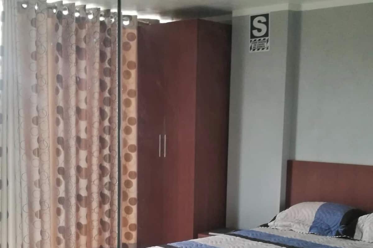 A bedroom with a bed, a wardrobe, and a curtain.