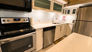 Una cocina moderna con electrodomésticos de acero inoxidable, armarios blancos y encimera de granito.