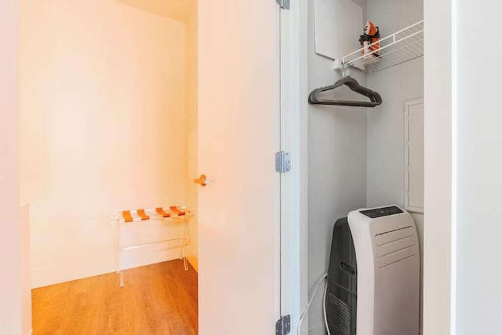 A room with a white door, a wooden floor, a white radiator, and a wall-mounted shelf with a few items.