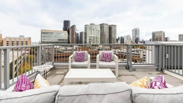 Eine Dachterrasse mit Blick auf die Stadtlandschaft, ausgestattet mit einer Couch und Stühlen sowie einem kleinen Tisch.