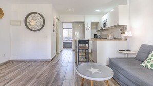 A modern living room with a grey sofa, a small round table with a star design, and a kitchen area with white cabinets and a coffee machine. - RentitSpain · Little Paradise on the Costa del Sol (Torremolinos)