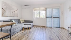 A modern living room with a grey sofa, a small round table, and a large abstract painting on the wall. - RentitSpain · Little Paradise on the Costa del Sol (Torremolinos)
