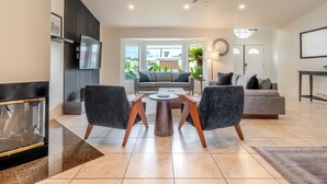A modern living room with a sofa, two armchairs, a coffee table, and a TV mounted on the wall. - Pool, Spa & Hot Tub! Golf Green 5BR near Coachella & Palm Springs-Jamaica Sands (Bermuda Dunes)
