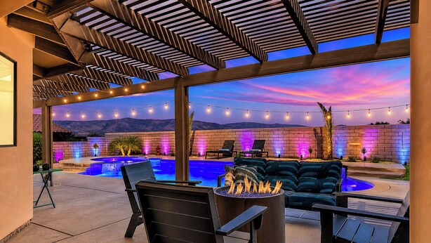 A poolside area with a fire pit, outdoor seating, and string lights. - Pool, Spa & Hot Tub! Golf Green 5BR near Coachella & Palm Springs-Jamaica Sands (Bermuda Dunes)