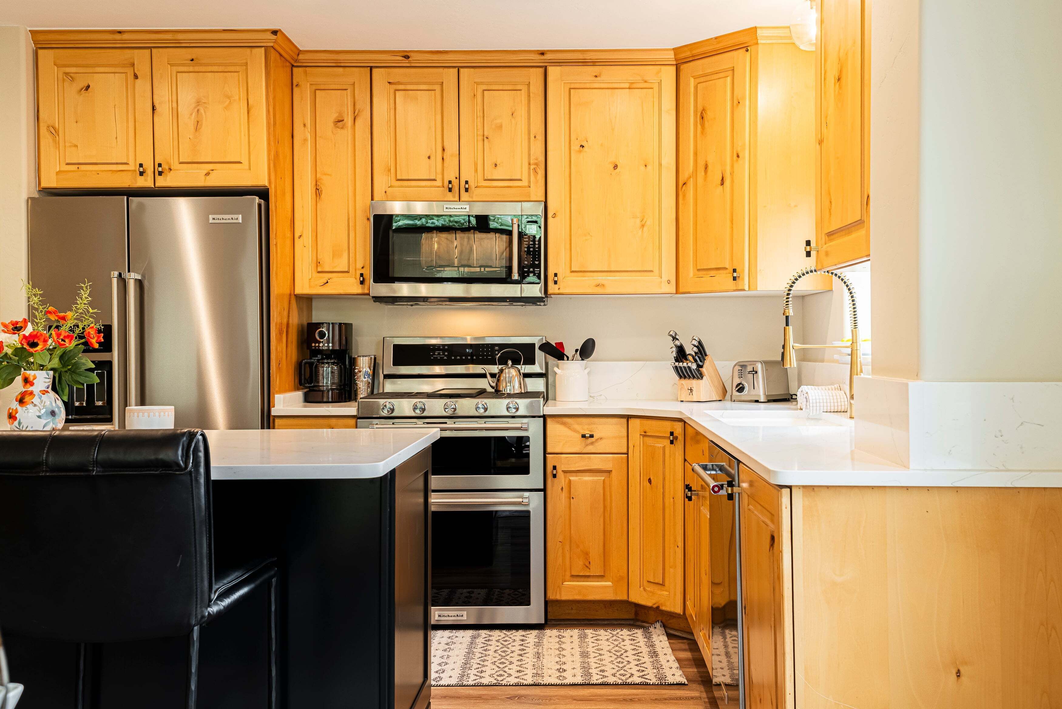 Una cocina con armarios de madera, un refrigerador de acero inoxidable, un microondas, una estufa y un lavaplatos.