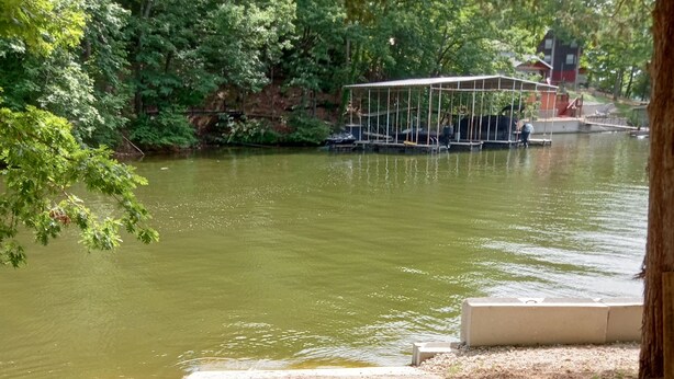 Une promenade le long de la rivière, avec un espace de repos abrité et un pont en arrière-plan.