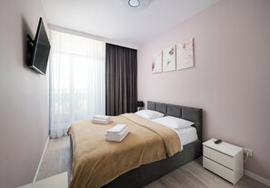 Relax in a serene space with a large bed, bedside table, and flat-screen TV.