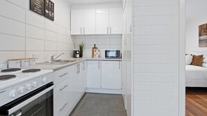 Une cuisine moderne avec des meubles blancs, un four à micro-ondes encastré et une cuisinière.
