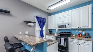 A compact kitchen with white cabinets, a microwave, a stove, and a sink. - Five-Minutes Flyover Cherry Point NC (Havelock)