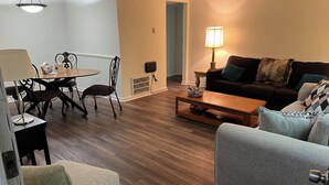 Un salon moderne avec un coin repas, comprenant un plancher en bois, un canapé, une table basse et une table à manger avec des chaises.