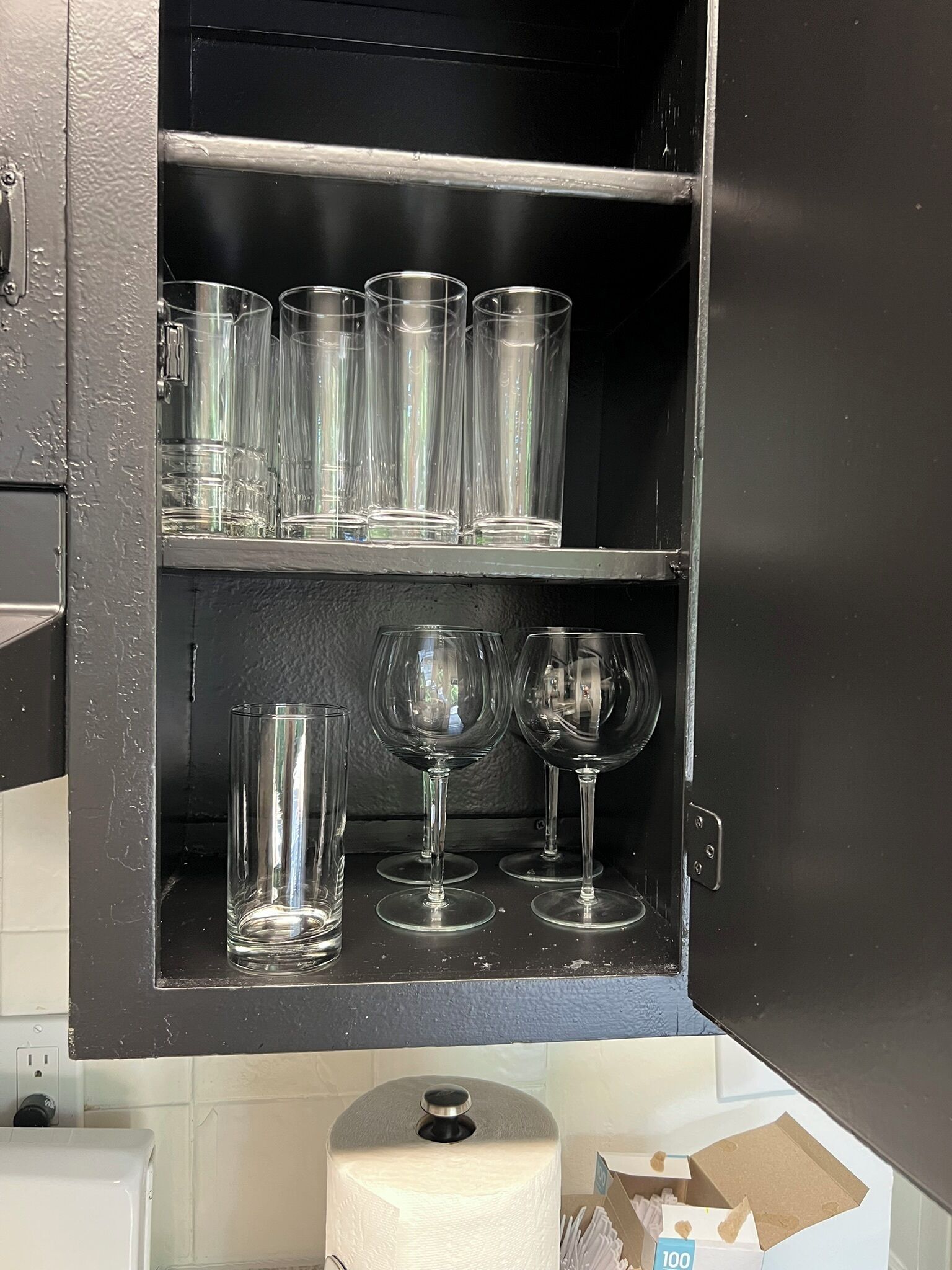 A cabinet with multiple shelves containing clear drinking glasses and wine glasses.