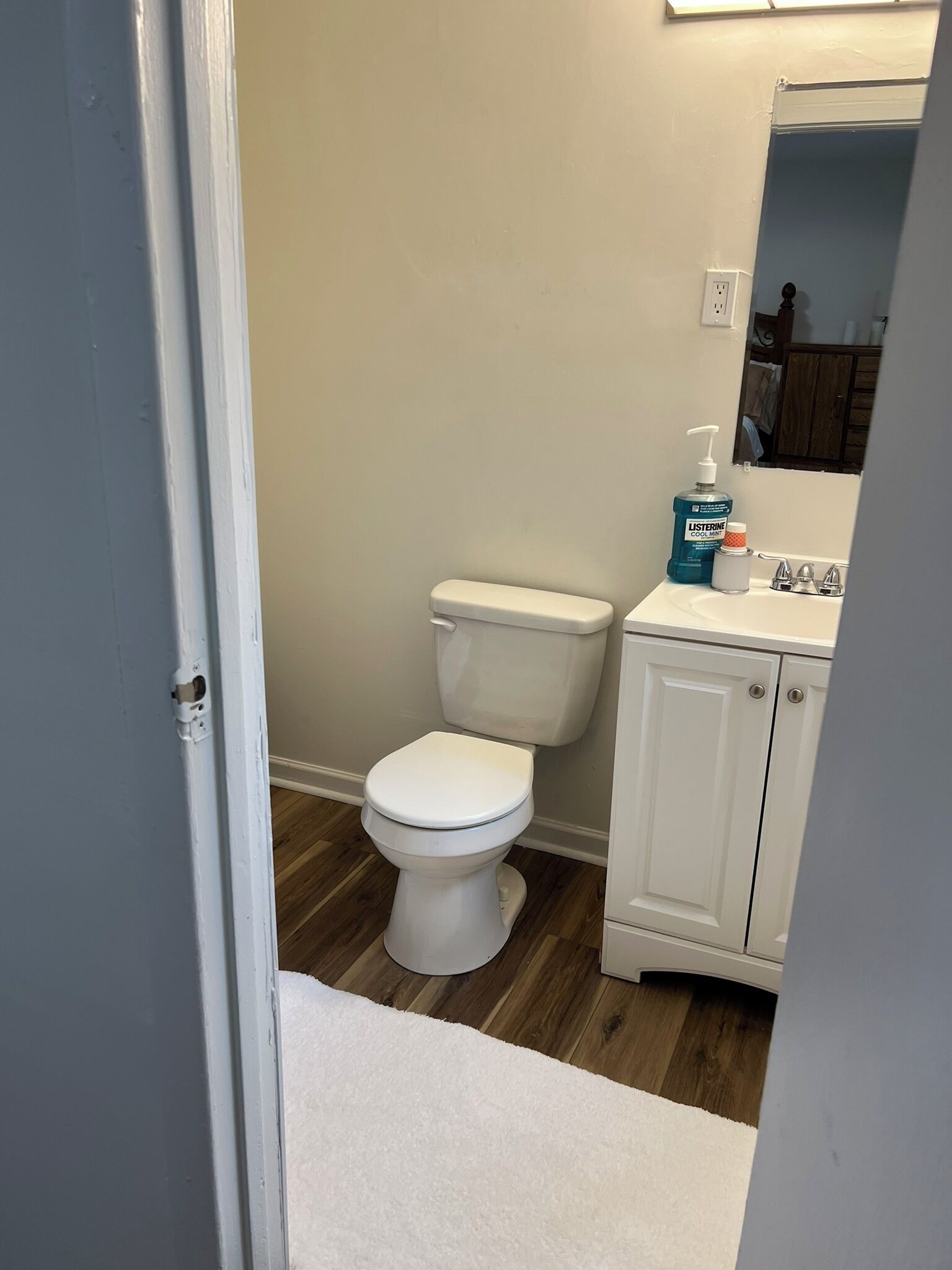 A bathroom with a white toilet, a sink with a mirror above it, and a cabinet with a white countertop.