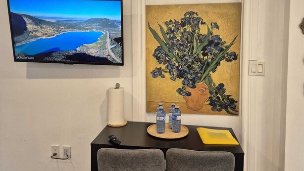 Un coin repas avec un téléviseur, un tableau et une table avec deux chaises.