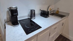 Une cuisine moderne équipée d’une plaque de cuisson à induction intégrée, d’une machine à café Keurig, d’un grille-pain et d’un évier.