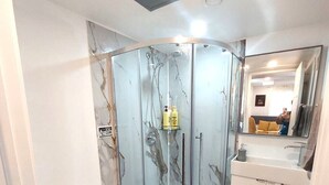 Une salle de bain avec une douche à parois de verre, des toilettes, un lavabo et un miroir.