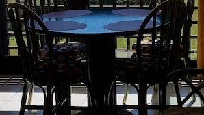 Un balcon avec une table et des chaises, une vue sur la mer et un rideau jaune.