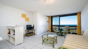 Une chambre avec un lit, une télévision, un bureau et un balcon offrant une vue.