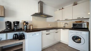 Cocina compacta con lavavajillas, lavadora, cafetera y microondas.