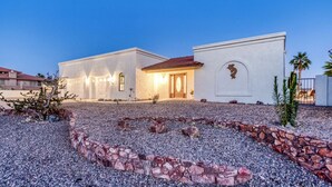 Una casa de dos pisos con techo de tejas rojas, paredes de estuco blanco y un camino de piedra que conduce a la entrada.