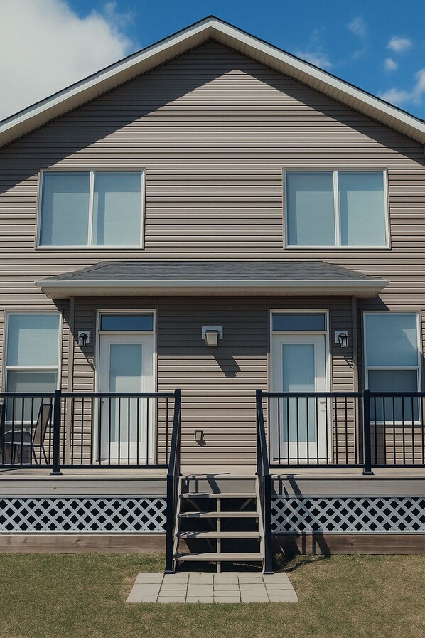 A two-story building with a flat roof, large windows, and a front porch with a railing.