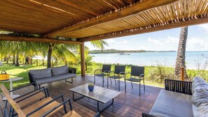 An outdoor deck with a wooden pergola, a sofa, chairs, and a table. - Mare Nostrum - Carneiros Beach - Ocean View - Balcony - 2 Suites - Eco Resort Condominium (Tamandare)