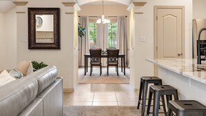 A modern kitchen with a marble countertop, a dining area with a chandelier, and a living room with a leather sofa. - The Knob Cozy Home (McKinney)