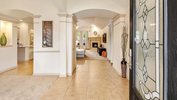 A spacious hallway with a tiled floor, a fireplace, and a decorative glass door. - The Knob Cozy Home (McKinney)