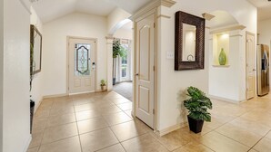 A spacious hallway with a tiled floor, a large mirror, and a potted plant. - The Knob Cozy Home (McKinney)