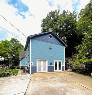 Un bâtiment à deux étages, à l’extérieur bleu, avec une porte d’entrée et un petit porche.