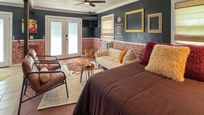 Amplia sala de estar con una cama grande, sillones de cuero, una mesa de centro y una chimenea.