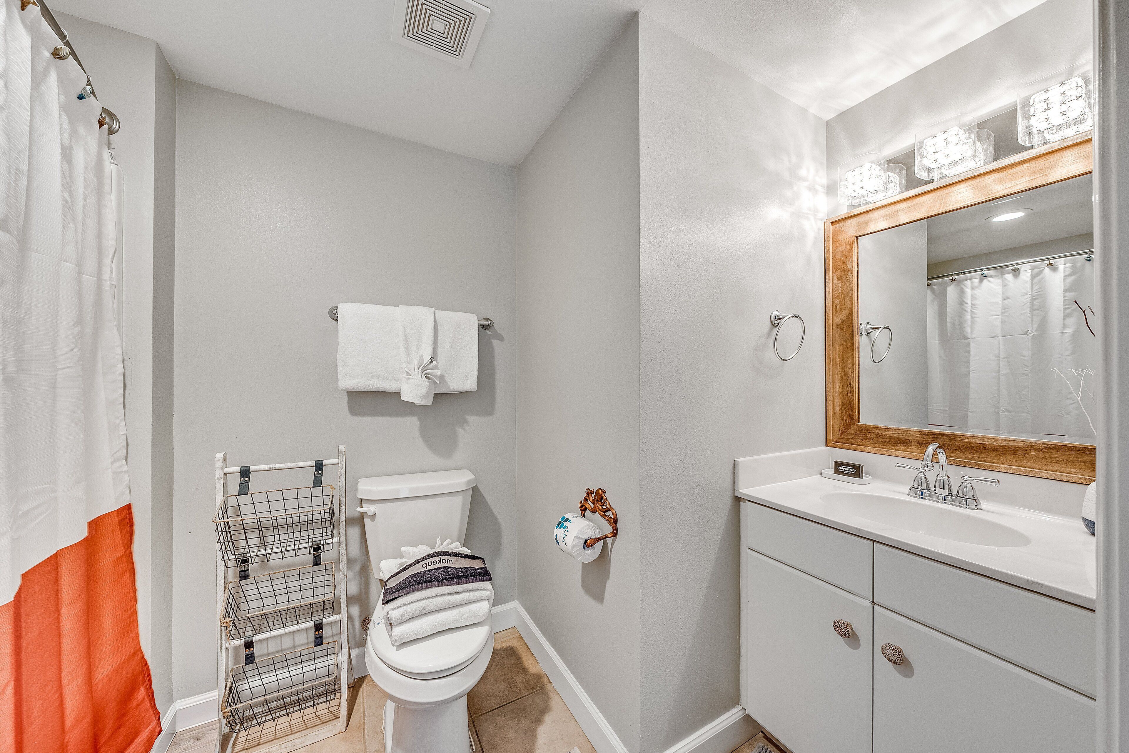 A bathroom with a white toilet, a sink with a mirror, and a shower curtain.