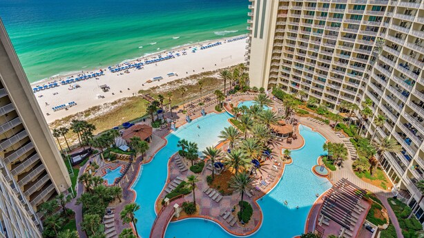 A high-rise hotel with a pool area, beach view, and multiple balconies.