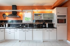 A modern kitchen with white cabinets, a black stove, and a microwave.