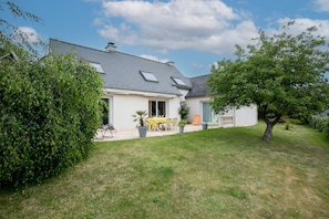 A house with a sloped roof, a patio with outdoor furniture, and a well-maintained lawn.
