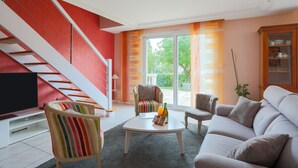 A living room with a sofa, chairs, a coffee table, a TV, and a staircase.