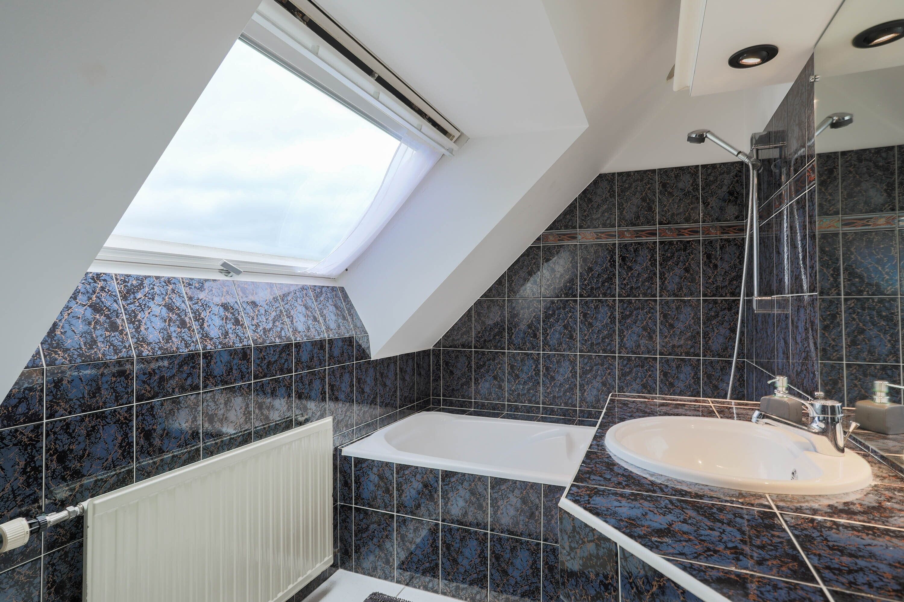 Un bagno moderno con una finestra a lucernario, una vasca e uno spazio doccia.