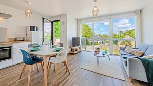Een modern appartement met een eethoek, keuken en woonkamer, voorzien van grote ramen.