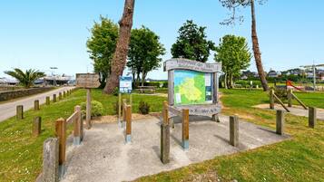 A park with a map sign, wooden fence, and trees.