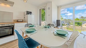 Een moderne keuken met een oven, een eettafel met stoelen en een uitzicht door een groot raam.