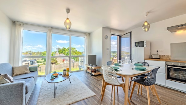 A modern apartment with a dining area, kitchen, and living room.