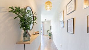 Un couloir agrémenté d’une plante, de tableaux encadrés et d’un luminaire suspendu.