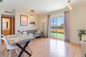 A modern living room with a dining area, large windows, and a view of the outdoors. - Apartment 'Sea Views - 2 Bedrooms' with Shared Pool, Wi-Fi and Air Conditioning (Benalmádena)