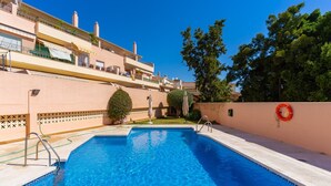 Une piscine avec une eau d’un bleu limpide, une bouée de sauvetage et un petit espace aménagé en jardin.
