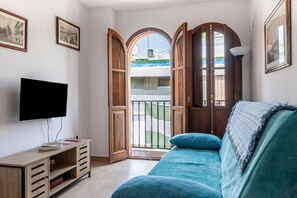 Un salon avec une télévision, un canapé et un balcon offrant une vue agréable.
