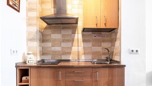 Une cuisine dotée de meubles en bois, d’une hotte de cuisinière en acier inoxydable, d’un évier et d’un dosseret carrelé.