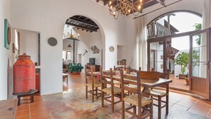 A dining area with a wooden table and chairs, a chandelier, and a large window with a view. - Vacation Villa 'Casa Rural La Molina' with Mountain View, Private Terrace and Wi-Fi (Máguez)