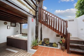 A spa area with a hot tub, wooden staircase, and potted plants.